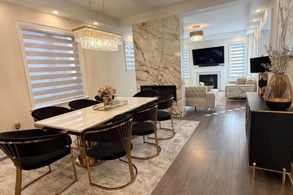 Dining room with a marble-top table, black chairs, fireplace, and living area beyond. - 1246 Pondside Trail, Oakville