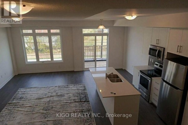 Open-concept living room and kitchen with a large island, stainless steel appliances, and a deck. - 1248 Restivo Lane, Milton