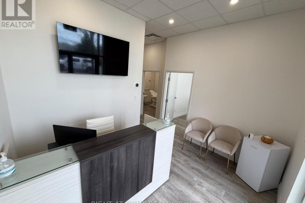 Reception desk with computer, chairs, and a doorway to another room - 125 - 701 Sheppard Avenue W, Toronto