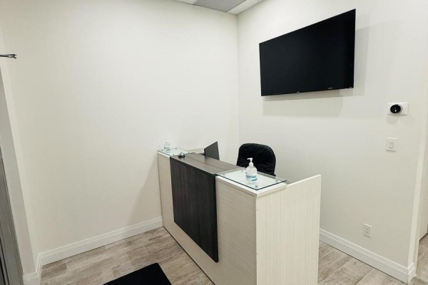Reception desk with a computer, hand sanitizer, and a wall-mounted TV - 125 - 701 Sheppard Avenue W, Toronto