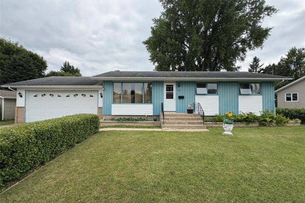 Front exterior view of a single-story house with a manicured lawn and hedges. - 125 Dunfield Avenue, Dauphin