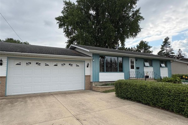 Close-up side view of a white garage door with decorative panels and concrete driveway. - 125 Dunfield Avenue, Dauphin