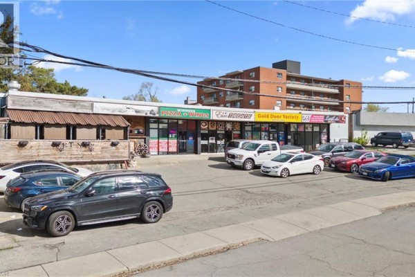 Front view of a commercial strip mall with businesses including a pizza place, tire shop, and convenience store. - 125 Gailmont Drive, Hamilton