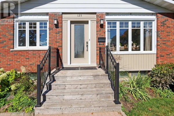 Close-up of the front entrance of a brick house with wooden steps and black metal railings. - 125 Juniper Street E, Ottawa