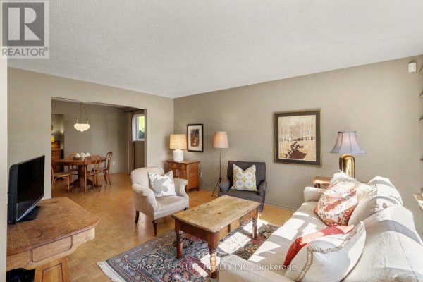 Living room furnished with a sofa, chairs, and a television, with a view into the dining area. - 125 Juniper Street E, Ottawa