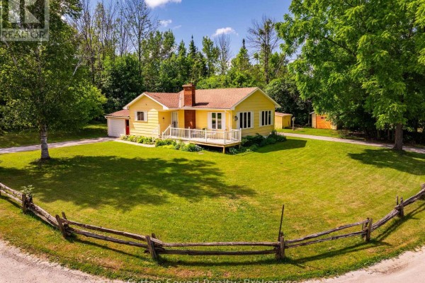 Aerial view of 125 Paradise Bay, Municipality of Meaford, showing the house, trees, and waterfront. - 125 Paradise Bay Road, Meaford