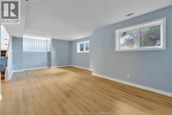 Finished basement with light wood floors, blue walls, and two windows - 125 Queen Street South Tilbury