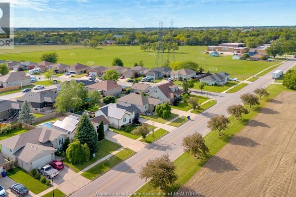 Aerial view of a suburban neighborhood with houses, solar panels, pool, school, and fields - 125 Queen Street South Tilbury