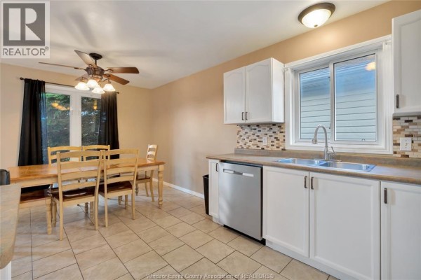 Kitchen with dining area, wooden table, white cabinets, double sink, and window - 125 Queen Street South Tilbury