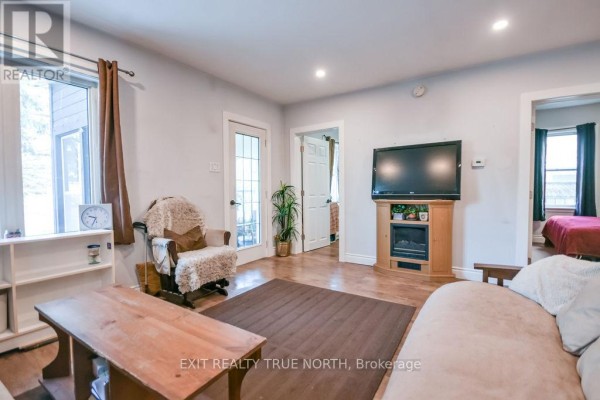 Living room featuring a television on a wooden stand, a fireplace, a rocking chair, and doorways to adjacent rooms. - 125 Queen Street W, Springwater