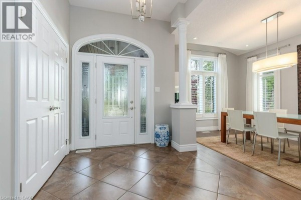 Modern kitchen with white cabinets, large island with sink, and stainless steel appliances. - 125 Woolner Trail, Kitchener