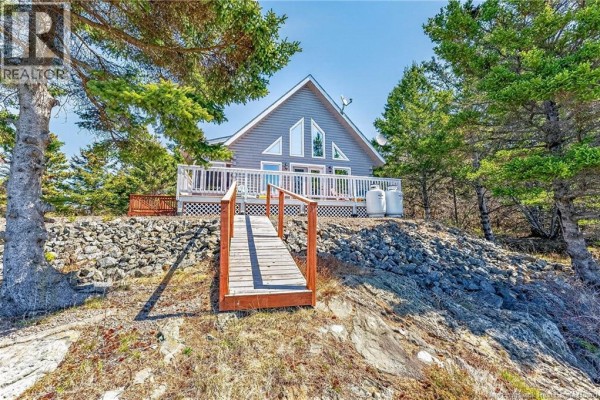 Close-up of glass double doors on a wooden deck with colorful chairs and propane tanks. - 1250 Route 172, L Etete