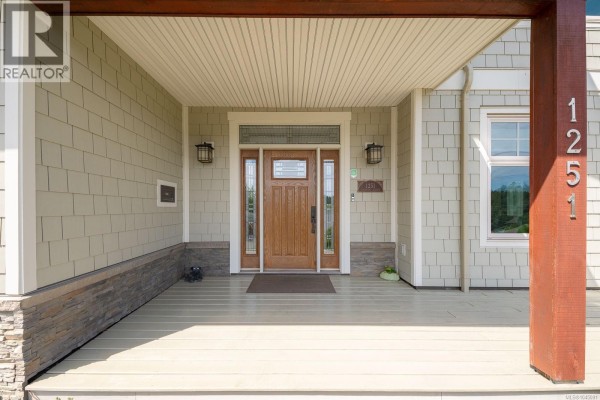 Side exterior of 1251 Discovery Ave, Nanaimo, with wooden deck and green landscaping. - 1251 Discovery Ave, Nanaimo
