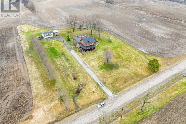 Aerial view of a farmhouse, garage, and outbuildings surrounded by fields. - 1251 Scugog Line 8, Scugog