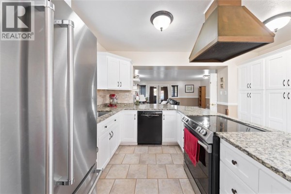 Kitchen with white cabinets, granite countertops, stainless steel appliances, and beige tile flooring. - 1252 Downie Road, Dawn Euphemia