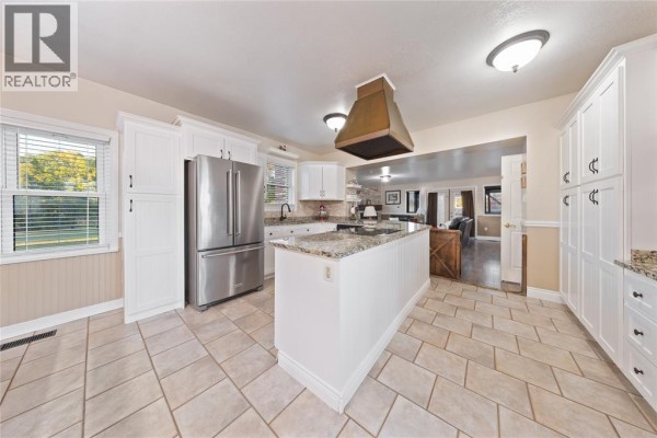 Kitchen with white cabinets, granite countertops, stainless steel appliances, and view into living area. - 1252 Downie Road, Dawn Euphemia