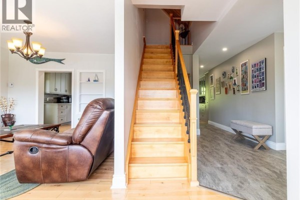 Living room featuring a leather recliner, wooden staircase, and access to the kitchen - 1253 Rte 772, Cummings Cove