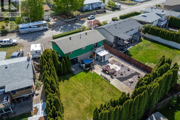 Aerial view of the backyard showing a green lawn, patio, and adjacent properties. - 1254 Heustis Drive, Ashcroft