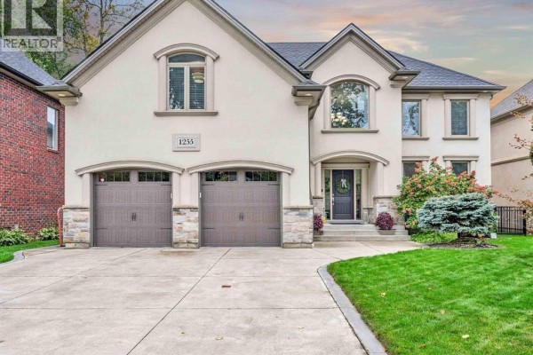 Front view of a luxurious house with a cream-colored facade, double garage doors, and professional landscaping. - 1255 Maple, Lasalle