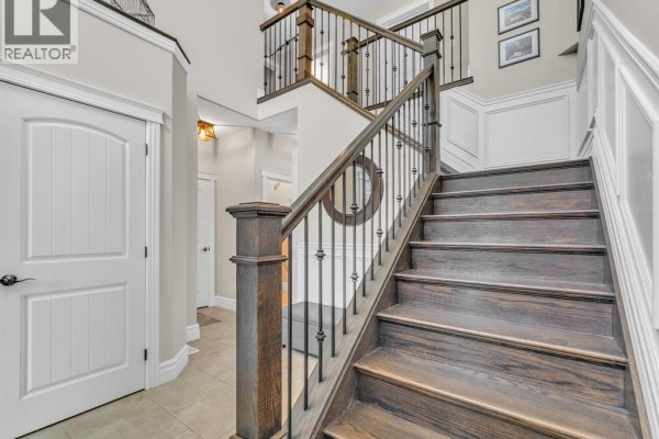 Hallway with a staircase, grey storage bench, decorative mirror, and a glimpse into a dining area. - 1255 Maple, Lasalle