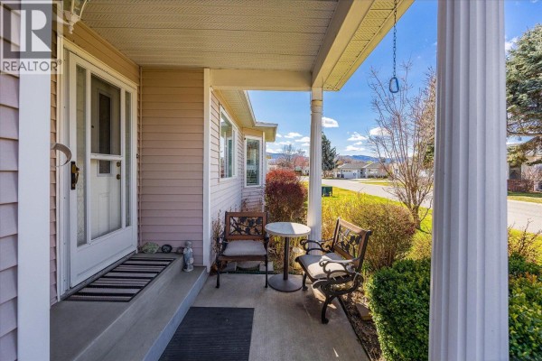 Covered front porch with seating, a small table, and a view of the street. - 1255 Raymer Avenue Unit# 493, Kelowna