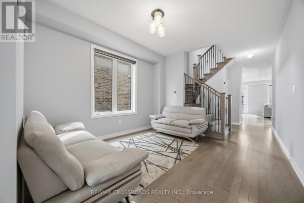 Living room with light grey walls, hardwood floors, and two cream sofas. - 1257 Aquarius Trail, Pickering