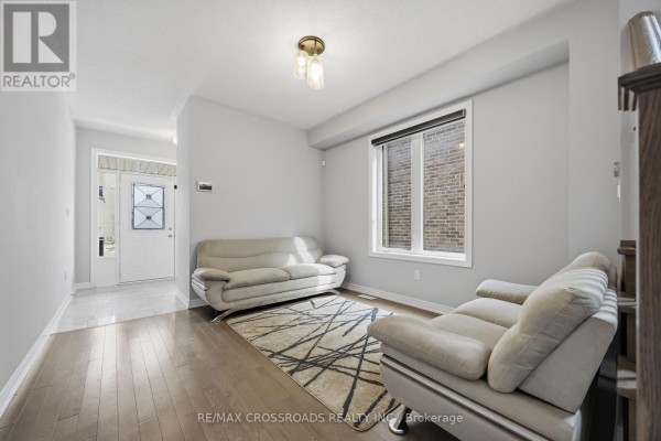 Living room with light grey walls, hardwood floors, and two cream sofas, viewed from the side. - 1257 Aquarius Trail, Pickering
