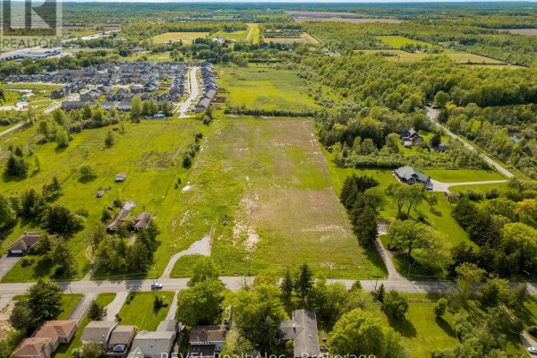 Aerial perspective of a large, cleared field with a suburban neighborhood nearby. - 1257 Pettit Road W, Fort Erie