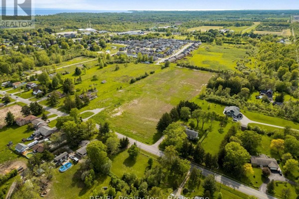 Aerial view of land with houses, trees, and a distant waterfront. - 1257 Pettit Road W, Fort Erie