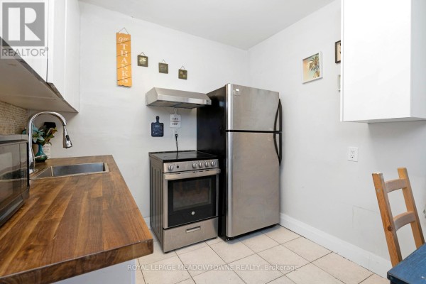 Kitchen area with gas stove, stainless steel fridge, and white cabinetry - 1259 Davenport Road, Toronto
