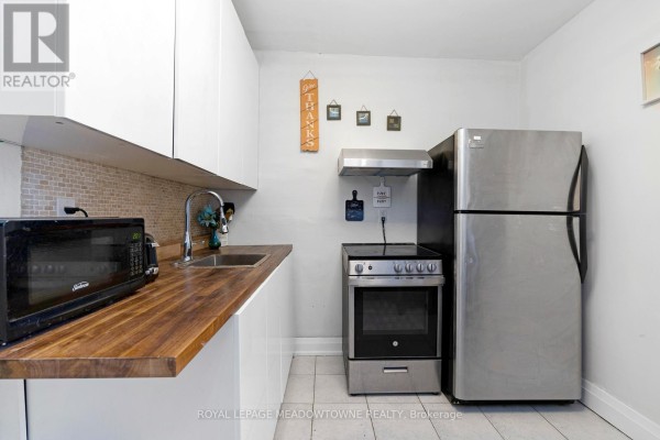 Kitchen with wooden countertop, microwave, and decorative wall art - 1259 Davenport Road, Toronto