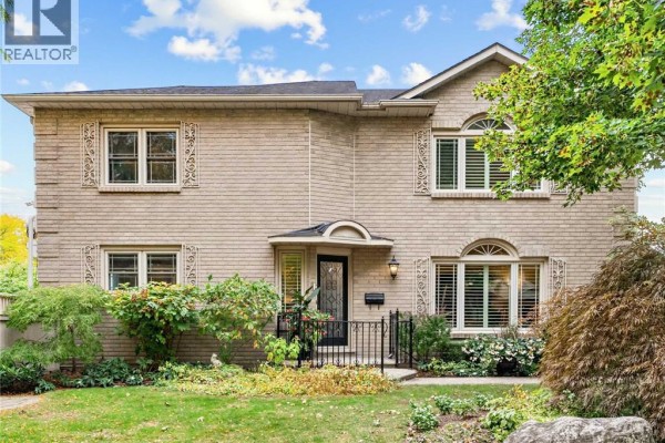 Close-up front view of the beige brick house facade with arched windows and a covered entryway. - 1259 Nathaniel Crescent, Burlington