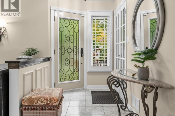 Interior entryway with tiled floor, bench, console table, oval mirror, and glass-paneled door. - 1259 Nathaniel Crescent, Burlington
