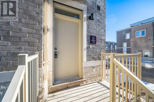 Close-up of a townhouse entrance door with beige door and grey brick facade. - 126 - 30 Almond Blossom Mews, Vaughan