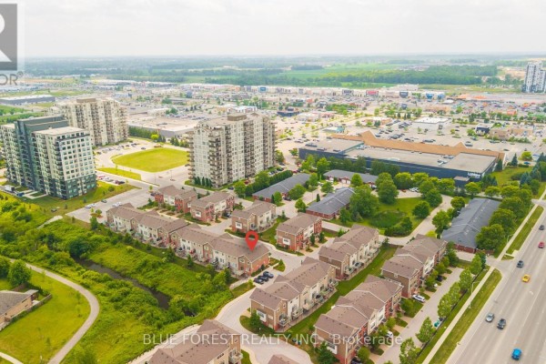 Aerial view of a suburban neighborhood with townhouses, high-rise buildings, and commercial areas. - 126 - 3025 Singleton Avenue, London South