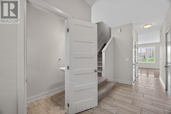 Interior hallway with light grey walls, beige wood-look tile flooring, and carpeted stairs. - 126 - 3025 Singleton Avenue, London South