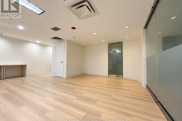 An empty commercial office space with white doors, light wood floors, and frosted glass partitions. - 126 - 7155 Woodbine Avenue, Markham
