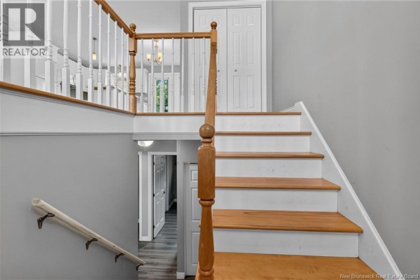 Interior staircase with white banisters, wooden steps, and grey walls. - 126 Bahama Street, Dieppe