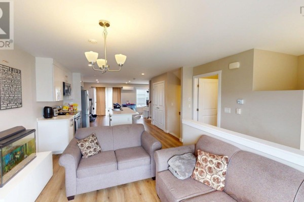 Open-concept living area with a kitchen island, sofas, and a view into the dining and kitchen areas. - 126 Cortland Ridge, Halifax