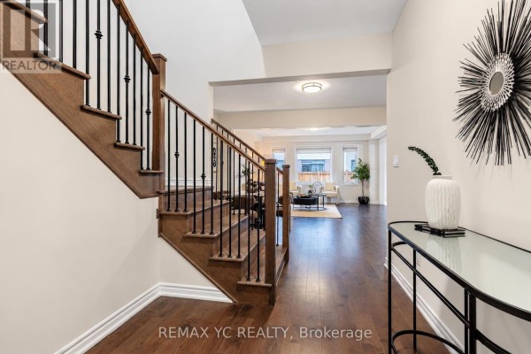 View from the foyer towards the living room, showing the staircase and hardwood floors. - 126 Durham Avenue, Barrie