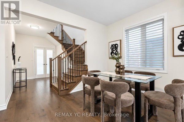 Dining area with a glass-top table, upholstered chairs, and a window with blinds. - 126 Durham Avenue, Barrie