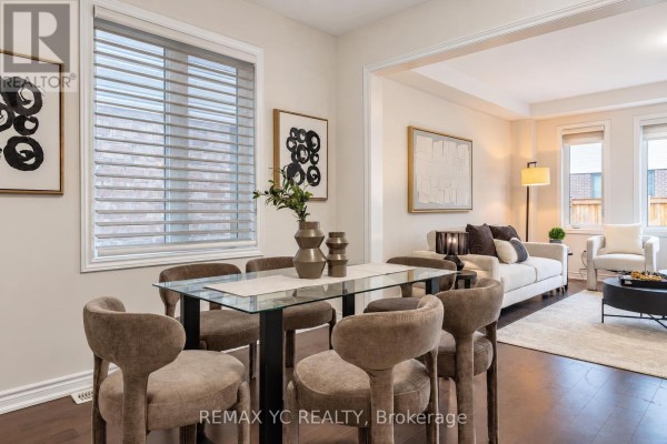 Dining area adjacent to a living room with a sofa, chairs, and decorative art. - 126 Durham Avenue, Barrie