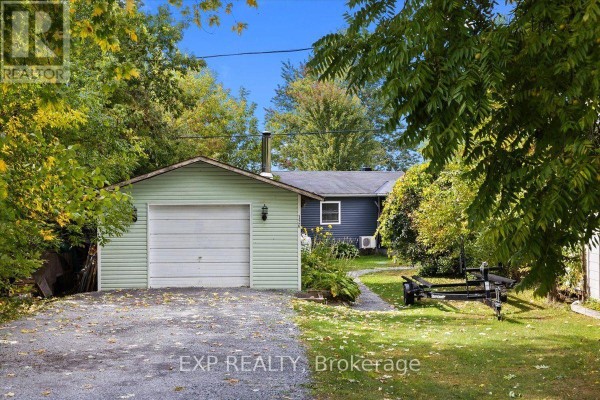 Detached light green garage with a single white garage door and white trim, adjacent to a driveway. - 126 Gardiner Shore Road, Beckwith