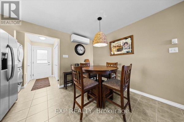 Kitchen area with a round wooden table and four chairs, beige walls, tiled floor, and a rattan pendant light. - 126 Gardiner Shore Road, Beckwith