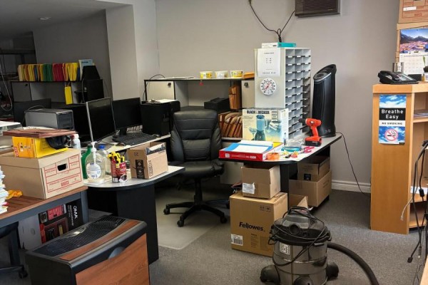 Office space with desks, computers, office supplies, boxes, and a vacuum cleaner. - 126 Main Street, Bluewater
