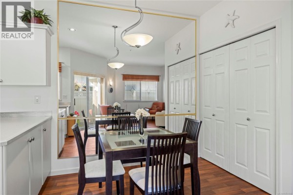 Dining area with a dark wood table, chairs, and large mirror reflecting the living room and kitchen. - 126 Ocean Walk Dr, Nanaimo