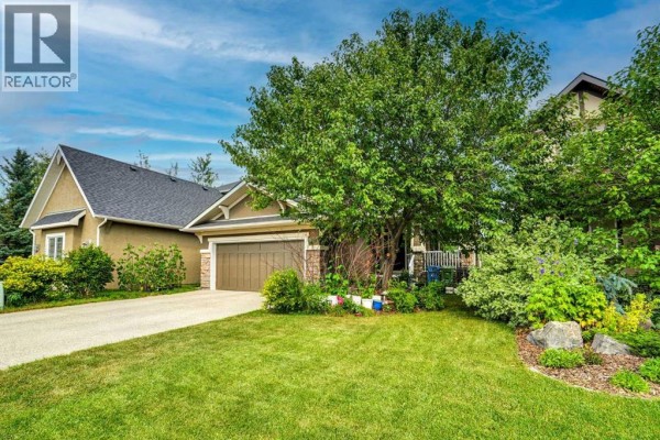 Daytime view of the front exterior with a well-manicured lawn and trees. - 126 Panatella Crescent Nw, Calgary