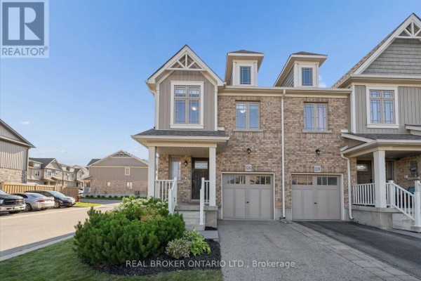 Low-angle view of the front exterior of a townhouse with stone and beige siding. - 126 Parkinson Crescent, Orangeville