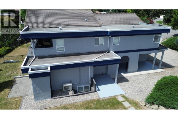 Side exterior view of the grey duplex with blue trim and attached garages. - 126 Verna Court, Kelowna