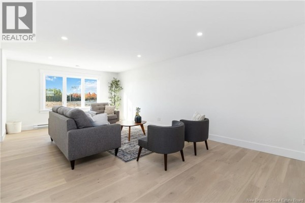 Living room with light wood floors, grey sofa and armchairs, and a coffee table. - 126 Whiterocks Drive, Riverview